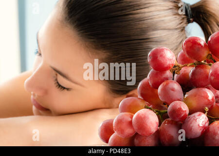 Close up Strauß roter Trauben mit Mädchen im Hintergrund. Mädchen in Aromatherapie in Wein Spa. Stockfoto