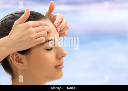 Therapeut tun alternative Heilmethoden auf junge Frau. Reiki Therapeuten berühren energetischen Bereich auf der Stirn. Stockfoto