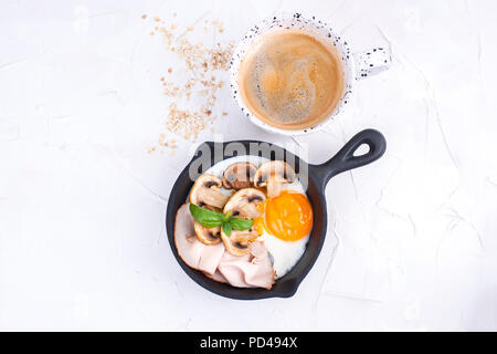 Leckeres, gesundes Frühstück. Spiegeleier mit Speck und Pilzen in einer kleinen Bratpfanne. Draufsicht. Speicherplatz kopieren. Stockfoto