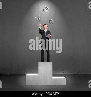 Unternehmer stehen auf dem Podium werfen und fangen 3D sliver Geld Symbole Stockfoto