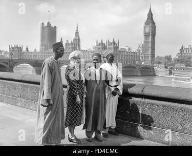 Juli 1950 19. London. England. Paramount Chiefs aus Sierra Leone Jaia Kaikai, Kai Samba, und Alkali Inodu III, ein Blick auf die Aussicht von der Terrasse der County Hall, bei einem Besuch in der Zentrale der London County Council. Mit den Leitern ist Frau Helen C. Bentwich, Stellvertretender Vorsitzender des Rates. Im Hintergrund kann man das Parlament und den Big Ben, über den Fluss. Die Leiter der sechs Woche Besuch in Großbritannien unter der Schirmherrschaft der britischen Rat etwas vom Leben in Großbritannien zu sehen. Stockfoto