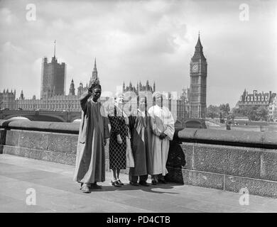 Juli 1950 19. London. England. Paramount Chiefs aus Sierra Leone Jaia Kaikai, Kai Samba, und Alkali Inodu III, ein Blick auf die Aussicht von der Terrasse der County Hall, bei einem Besuch in der Zentrale der London County Council. Mit den Leitern ist Frau Helen C. Bentwich, Stellvertretender Vorsitzender des Rates. Im Hintergrund kann man das Parlament und den Big Ben, über den Fluss. Die Leiter der sechs Woche Besuch in Großbritannien unter der Schirmherrschaft der britischen Rat etwas vom Leben in Großbritannien zu sehen. Stockfoto