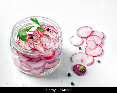 Die rosa Rettich ist in Stücke sorgfältig in einem Glas mit Schichten von Zitronensaft und Pflanzenöl auf Top platziert Grün festgelegt. Stockfoto
