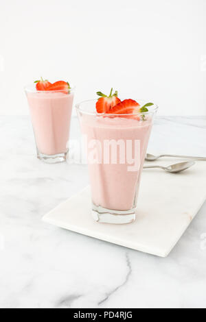 Zwei highball Gläser mit hausgemachten Erdbeer Mousse auf einem Marmor und weißem Marmor Hintergrund gefüllt. Stockfoto