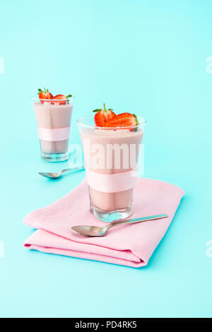 Zwei highball Gläser mit hausgemachten Erdbeer Mousse gefüllt auf hellblauem Hintergrund mit kopieren. Stockfoto