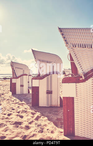 Vintage getonten Bild der Wicker hooded Warenkorb Stühle am Strand bei Sonnenuntergang, Sommerferien Konzept. Stockfoto