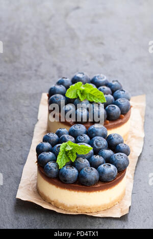 Zwei mini Schokolade Käsekuchen mit frischen Heidelbeeren auf schwarzen Stein Hintergrund Stockfoto