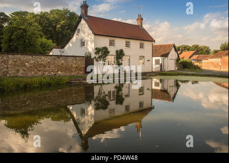 Ein Haus ist von einem Teich im Dorf von Bischof Burton wider, East Riding von Yorkshire, Vereinigtes Königreich, am Donnerstag, den 2. August 2018, Stockfoto