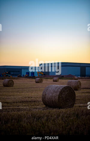 Heu Stroh auf Ackerland mit Industrial Site im Hintergrund entwickelt. Stockfoto