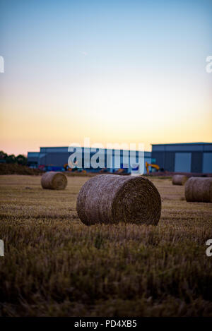 Heu Stroh auf Ackerland mit Industrial Site im Hintergrund entwickelt. Stockfoto