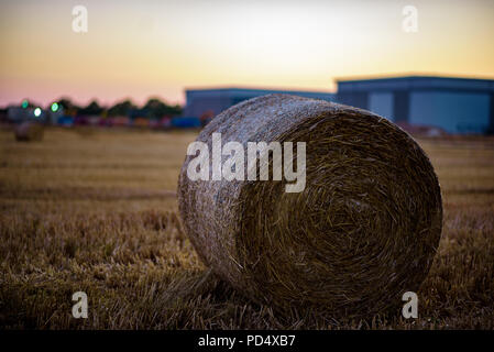 Heu Stroh auf Ackerland mit Industrial Site im Hintergrund entwickelt. Stockfoto