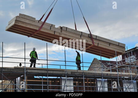 Silhouetten von Bauarbeitern auf der Oberseite des neuen Entwicklung mit großen Holz Lieferung Stockfoto
