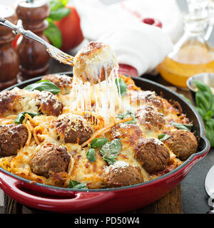 Gebackene Hackfleischbällchen mit Spaghetti, Tomatensauce, Basilikum und Käse mit Käse gezogen Stockfoto