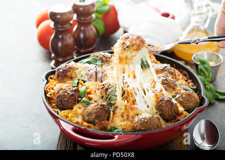 Gebackene Hackfleischbällchen mit Spaghetti, Tomatensauce, Basilikum und Käse mit Käse gezogen Stockfoto