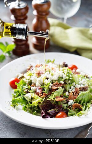 Grüner Salat Salat mit blauen Käse und Speck mit dressin über Gießen Stockfoto