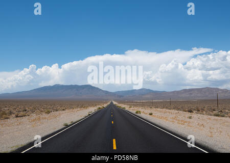 Desert highway verschwinden in Perspektive in ein Gebirge unter dramatischen Blauer Himmel und weiße Wolken in westlichen Nevada Stockfoto