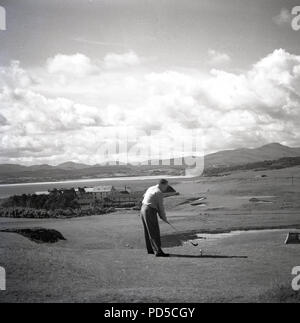 1950er Jahre, männlicher Golfspieler auf einem T-Stück an der Küste gof Kurs über Zu- oder Abschlag, Irland. Stockfoto