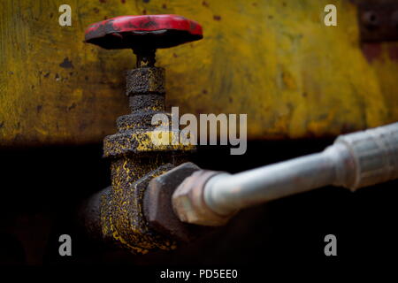 Eine ölige, schmutzig und baufälligen Hydraulikventil am Auslass von einem Vorratsbehälter für Öl, auf einem unbenutzten Kran-LKW gefunden Stockfoto