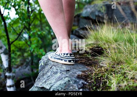 Das Mädchen ist zu Fuß entlang dem Rand der Klippe. Das ist sehr gefährlich und es ist atemberaubend. Es geht langsam, damit Sie nicht von den Höhen fallen Stockfoto