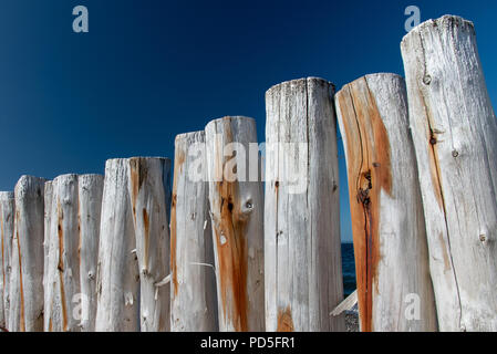 Verwitterte Wellenbrecher Wand in der frühen Morgensonne gegen deep blue sky Stockfoto