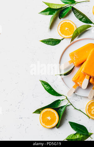 Hausgemachte orange Eis auf Stick. weißen Hintergrund mit orange Früchte Schichten und orange tree verlässt. Stockfoto