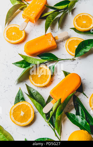 Hausgemachte orange Eis auf Stick. weißen Hintergrund mit orange Früchte Schichten und orange tree verlässt. Stockfoto