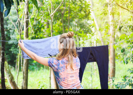 Junge weiße Mädchen heraus hängen die Kleidung zu Trocknen nach dem Waschen im Garten, Haushalt Aufgaben Stockfoto