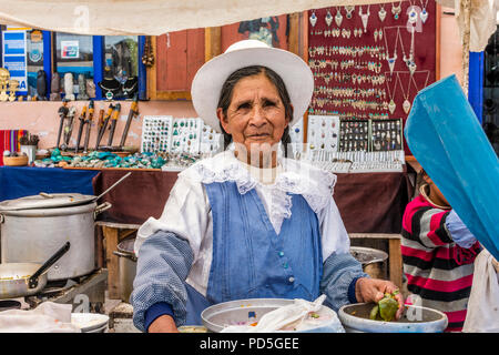 Lokale Reife der peruanischen Frau mit Zöpfen und Hut, bereitet das Essen in den lokalen Markt in Pisac, Peru, Südamerika. Stockfoto