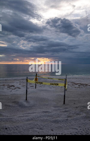 Sonnenuntergang hinter einem umzäunten Turtle Nest auf Clam Pass Strand in Naples, Florida Stockfoto