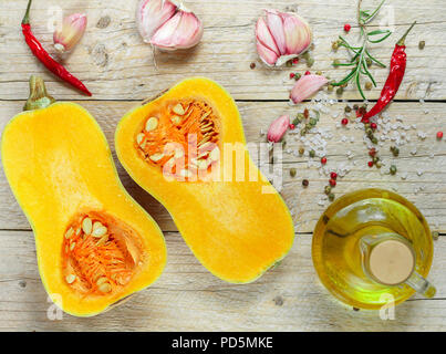 Raw organic butternut squash mit Zutaten zum Kochen auf einem Holztisch. Selektive konzentrieren. Im rustikalen Stil Stockfoto