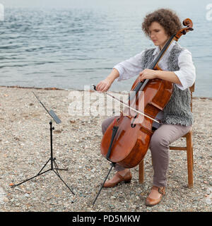 Frau spielt das Cello am Meer Stockfoto