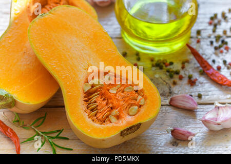 Raw organic butternut squash mit Zutaten zum Kochen auf einem Holztisch. Selektive konzentrieren. Im rustikalen Stil Stockfoto