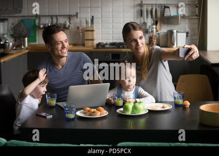 Glückliche Familie mit Kindern, die auf dem Telefon in breakfa selfie Stockfoto