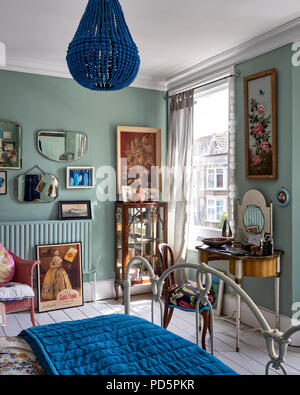 Vintage Spiegel und Artwork von Jo Oakely an der Wand im Schlafzimmer im Little Greene's Schrank grün lackiert. Die blaue Perle Kronleuchter ist von Graham & Stockfoto