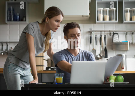 Junge schwere Paar diskutieren inländischen Rechnungen mit Papieren und l Stockfoto