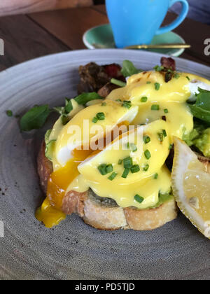 Ei Pochierte auf Brot, Speck und Zitrone auf eine graue Platte Stockfoto