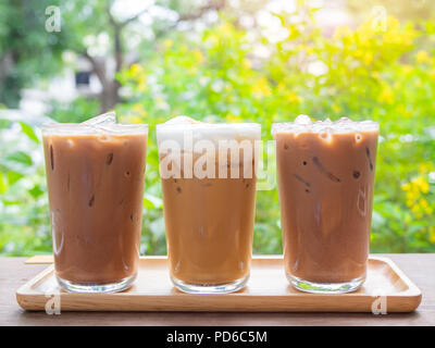 Drei Gläser Eiskaffee auf Holztisch auf grünen Garten Hintergrund im Cafe. Stockfoto