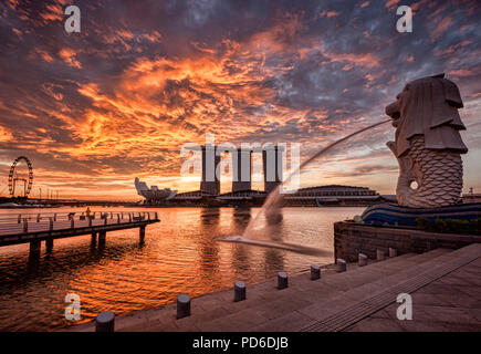 Skyline von Singapur bei Sonnenaufgang, mit der Merlion, das Marina Bay Sands, der Kunst und Wissenschaft Museum und der Singapore Flyer, alle unter einem dramatischen Sunrise Stockfoto