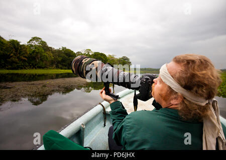 Naturfotograf mit großen Teleobjektiv in einem Boot auf dem Rio Chagres, Soberania Nationalpark, Republik Panama. Stockfoto