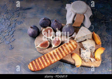 Reifen Feigen, edle Käse mit Schimmel, Pfirsich Schichten und Baguette auf einem Schneidebrett. Stockfoto