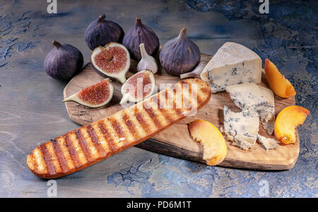 Reifen Feigen, edle Käse mit Schimmel, Pfirsich Schichten und Baguette auf einem Schneidebrett. Stockfoto