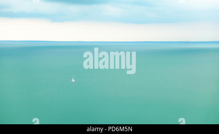 Lonely Segelboot auf türkisfarbenem Wasser segeln unter hellen Himmel Stockfoto