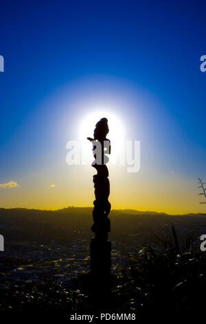 Maori Kunst Hand geschnitzte Statue in Wellington mit Blick über die Stadt scape bei Sonnenuntergang blaue Stunde repräsentativen für die Neuseeländische Kultur der Ureinwohner Stockfoto