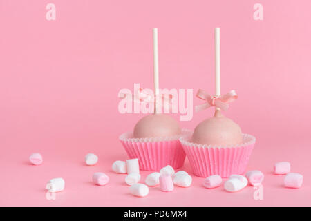 Paar festliche Sahnehäubchen kuchen Pops und Marshmallows über rosa Hintergrund, Konzept der Valentinstag Stockfoto