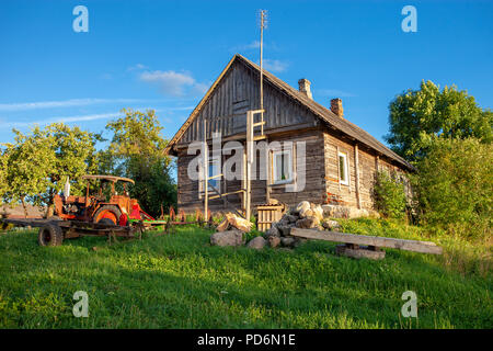 Typische litauische Holzhaus mit alten Traktor auf dem Land auf einem sommerlichen Abend Stockfoto