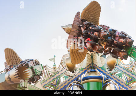 Kopenhagen, Dänemark - Juli 5, 2017. Kinder auf einem Karussell, Tivoli Gärten bei Sonnenuntergang. Dekorativ verzierten Vogel in einem Vergnügungspark. Stockfoto
