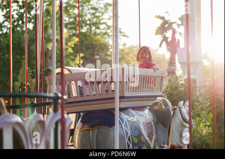 Kopenhagen, Dänemark - Juli 5, 2017. Kind auf einem Karussell zu einem Karneval oder Festival bei Sonnenuntergang. Dekorativ verzierten Elefant, Tiere in einem Vergnügungspark. Stockfoto