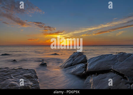 Meer Läppen um die Felsen bei Sonnenuntergang Stockfoto