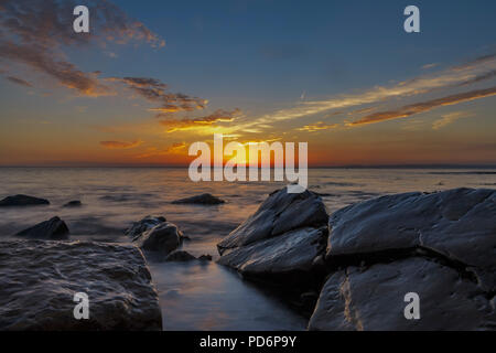 Meer Läppen um die Felsen bei Sonnenuntergang Stockfoto