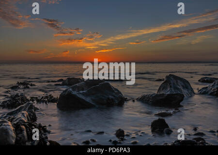 Meer Läppen um die Felsen bei Sonnenuntergang Stockfoto